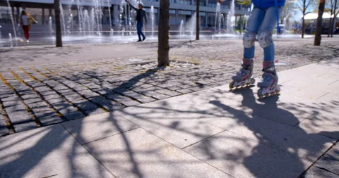 A child on roller skates rides on a sidewalk with stone tiles Stock Footage 119565812