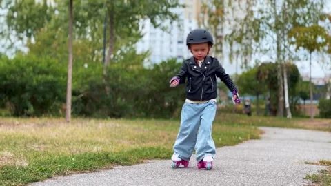 Child roller skating on a park path outdoors Stock Footage 345634005