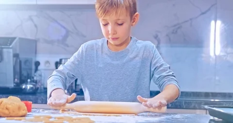 Child  rolling dough with a rolling pin, close up view. Boy rolls out the dou Stock Footage 127648940