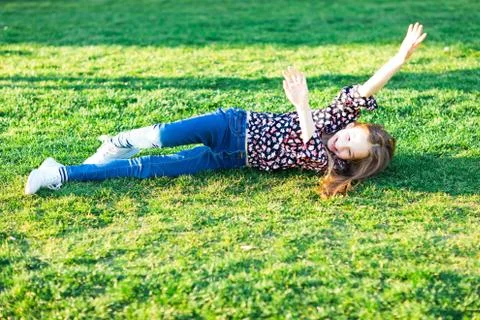 Child rolling down hill in grass - having fun during summer day Stock Photos