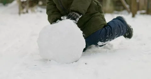 Child rolling large snowball in winter scene Stock Footage 286051523