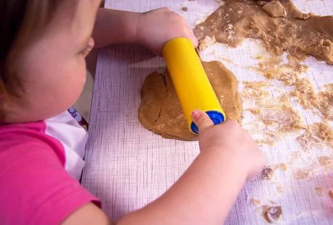 Child rolling out dough to bake cookies Stock Photos