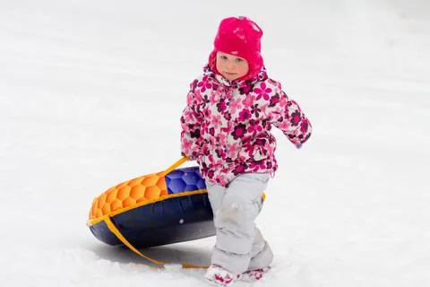 Child rolls down snow hill Stock Photos