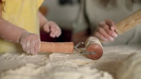 The child rolls out the dough on the table using a roller. Stock Footage 188241554