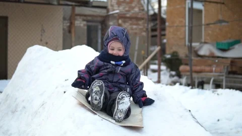 A child rolls on a snow slide. Winter fun on the street. In the cold winter, the 스톡 동영상 122255933