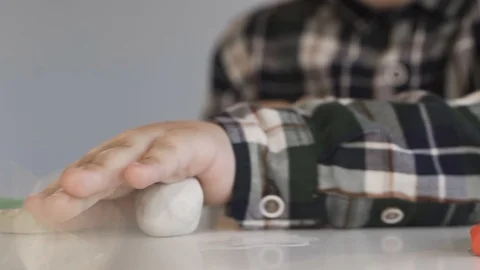 A child rolls a white piece of plasticine on a white table Stock Footage 124941535