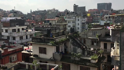 Child on rooftop attempts to fly a kite amidst dense urban housing Vídeo Stock 336408891