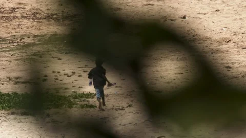 Child running on beach with a plastic bottle and plant foreground Stock Footage 126955779