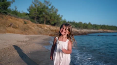 Child running joyfully along the beach in bright sunlight Видео 341119337