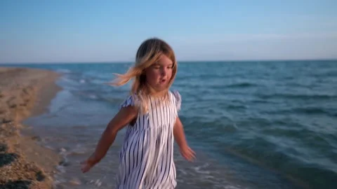 Child running joyfully along the beach at sunset Видео 341119577