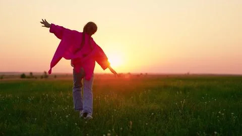 Child running in park. Slow motion. Girl child runs across green grass towards Stock Photos