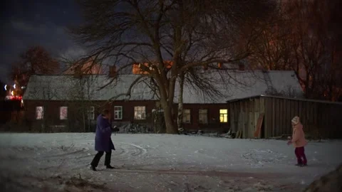 Child Running Through Snow by Old Brick Building at Night in Daugavpils Stock Footage 327924543