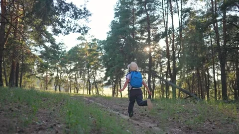 Child running through summer forest. Boy wears backpack, boy wears hat. Forest Vídeos de archivo 316717899
