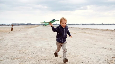 Child running with toy airplane. Kid boy playing with plane outdoors. Stock Footage