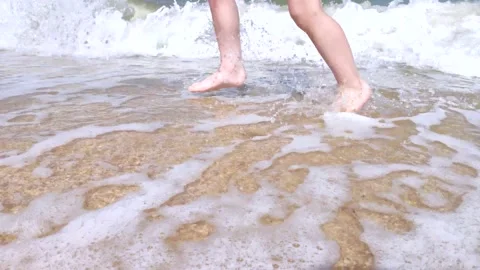 A child runs along the waves. Macro video of children's feet that run through th Stock Footage 132707145