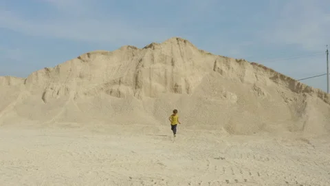 A child runs as fast as possible with a big pile of sand behind, in France Stock Footage 226214700