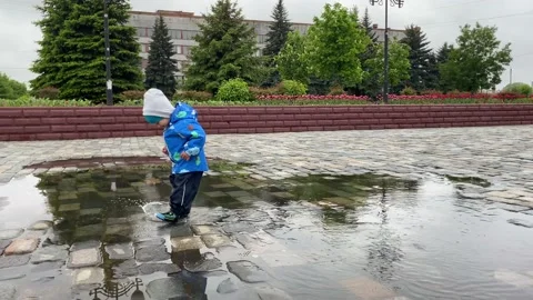 A child runs into a large puddle Stock Footage 131329614