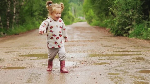 The child runs through puddles in rubber boots Stock Footage 113048455