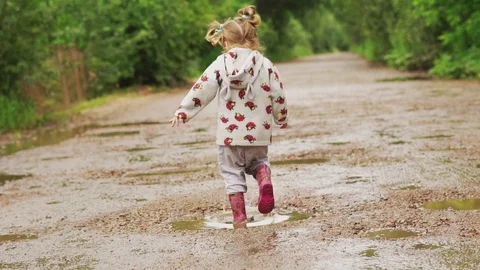 The child runs through puddles in rubber boots Stock Footage 115773738