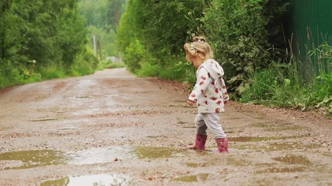 The child runs through puddles in rubber boots Stock Footage 116018921