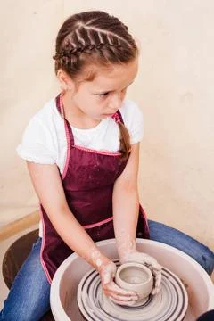 Child s ceramic handicrafts Girl makes pottery from white clay on a potter... Stock Photos