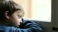 child sad and lonely looking through window HD Footage