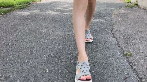 A child in sandals is walking on the asphalt. Legs close up Stock Footage 162018341