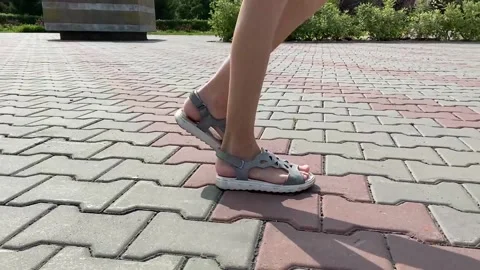 A child in sandals walks along the cobblestones. Legs close up Stock Footage 166314163