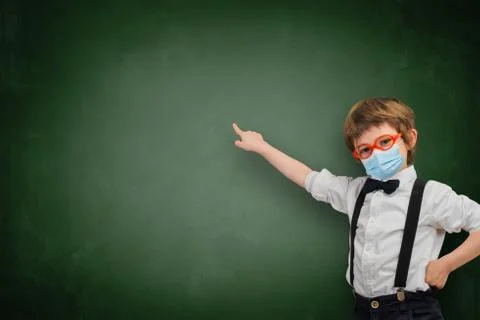 Child with sanitary mask points an empty whiteboard. Stock Photos