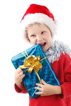 Child in santas cap biting a present Stock Photos