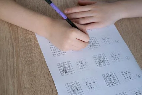 Child, schoolboy solves math examples in a column, makes arithmetic calculati Stock Photos