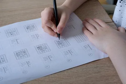 Child, schoolboy solves math examples in a column, makes arithmetic calculati Stock Photos