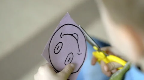 Child with scissors cuts from the paper smiley Stock Footage 60816365