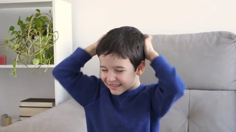 Child scratching head sitting on a sofa Vidéo 251655892