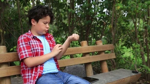 Child scratching his self at park 2 Stock Footage 75334045