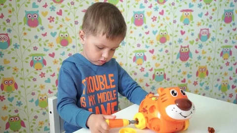 Child with a screwdriver assemble the toy Stock Footage 75890131