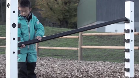 Child setting a hurdle height lower Stock Footage 221100876