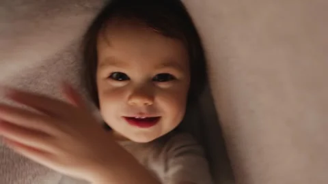 Child shines flashlight under blanket in room. Toddler smiles brightly and looks Stock Footage 311246480