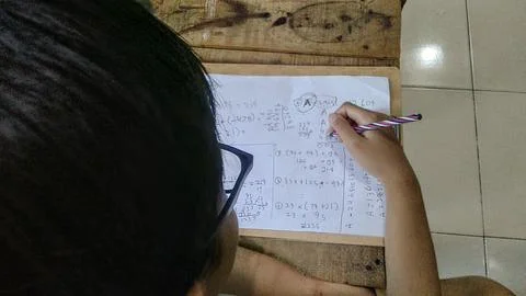A child is shown completing a math assignment, with paper and pen Fotos Stock