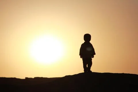 Child silhouetted at sunset Stock Photos
