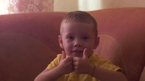 The child sits on the bed and makes cool gestures with his hands Stock Footage 285947232