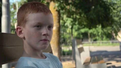 A child sits on a bench and chews gum Stock Footage 250152991