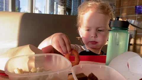 Child sits in the café and eats the onion rings Stock Footage 279502242