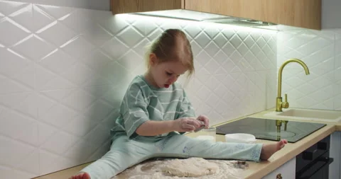 Child sits kitchen counter, rolling dough Video stock 333523760