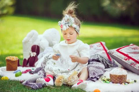 Child sits on a meadow around Easter decoration Stock Photos
