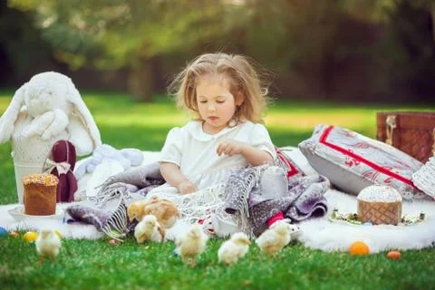 Child sits on a meadow around easter decoration Stock Photos