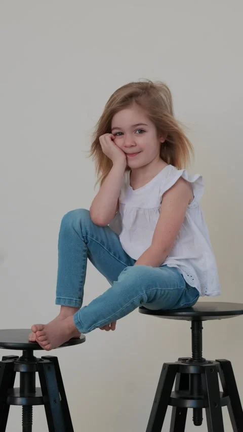 Child sits playfully on stool and enjoys a carefree moment at home Stock Footage 308659273