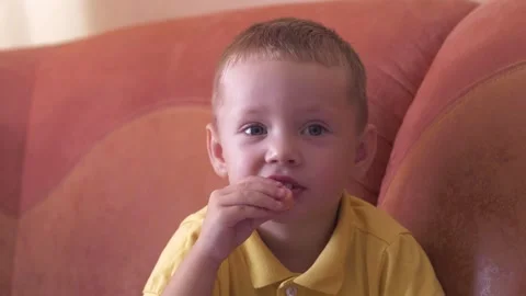 Child sits on sofa and eats food, sausage close-up Stock Footage 285948118