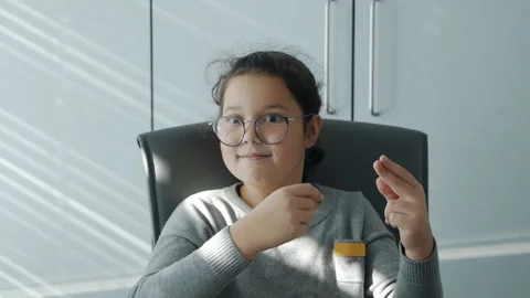 The child sits at the table and plays with rubber bands, does not want to do Stock-Footage 164107270