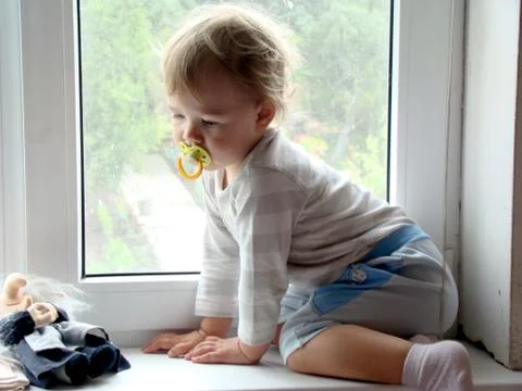 The child sits on the window Stock Photos